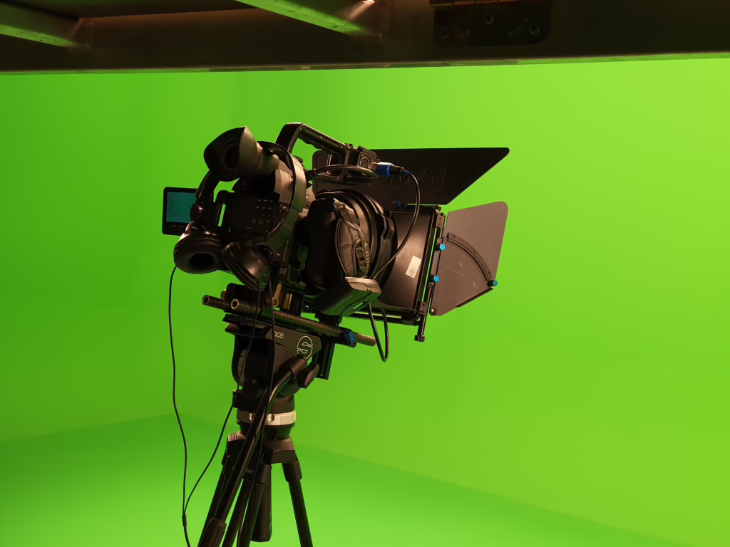Professional broadcast camera with matte box set up in front of a green screen in a TV studio